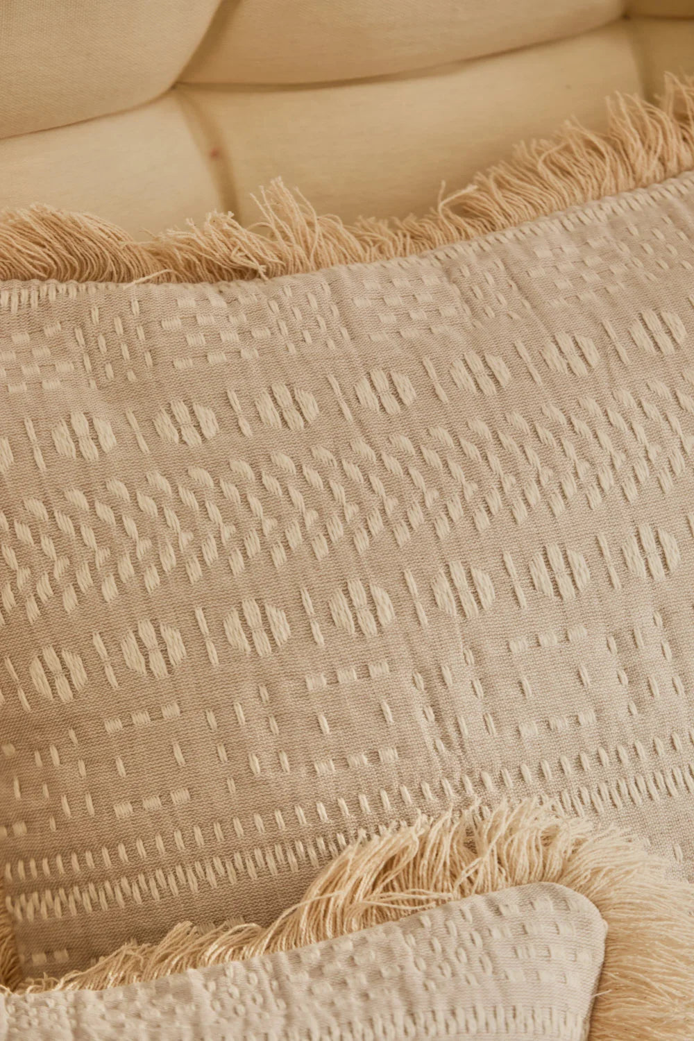 Funda cojín 60x60 de algodón jacquard beige con detalles en crudo y acabado en flecos detalle tela