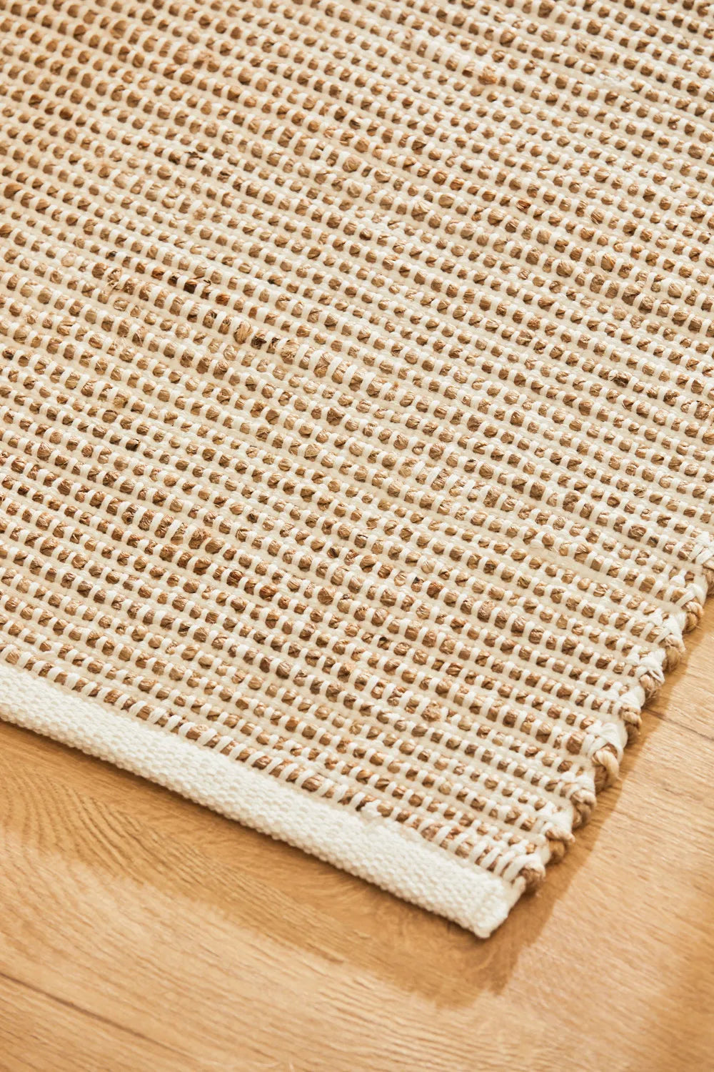 Alfombra de yute y algodón color crudo, con trenzado artesanal y una textura natural detalle