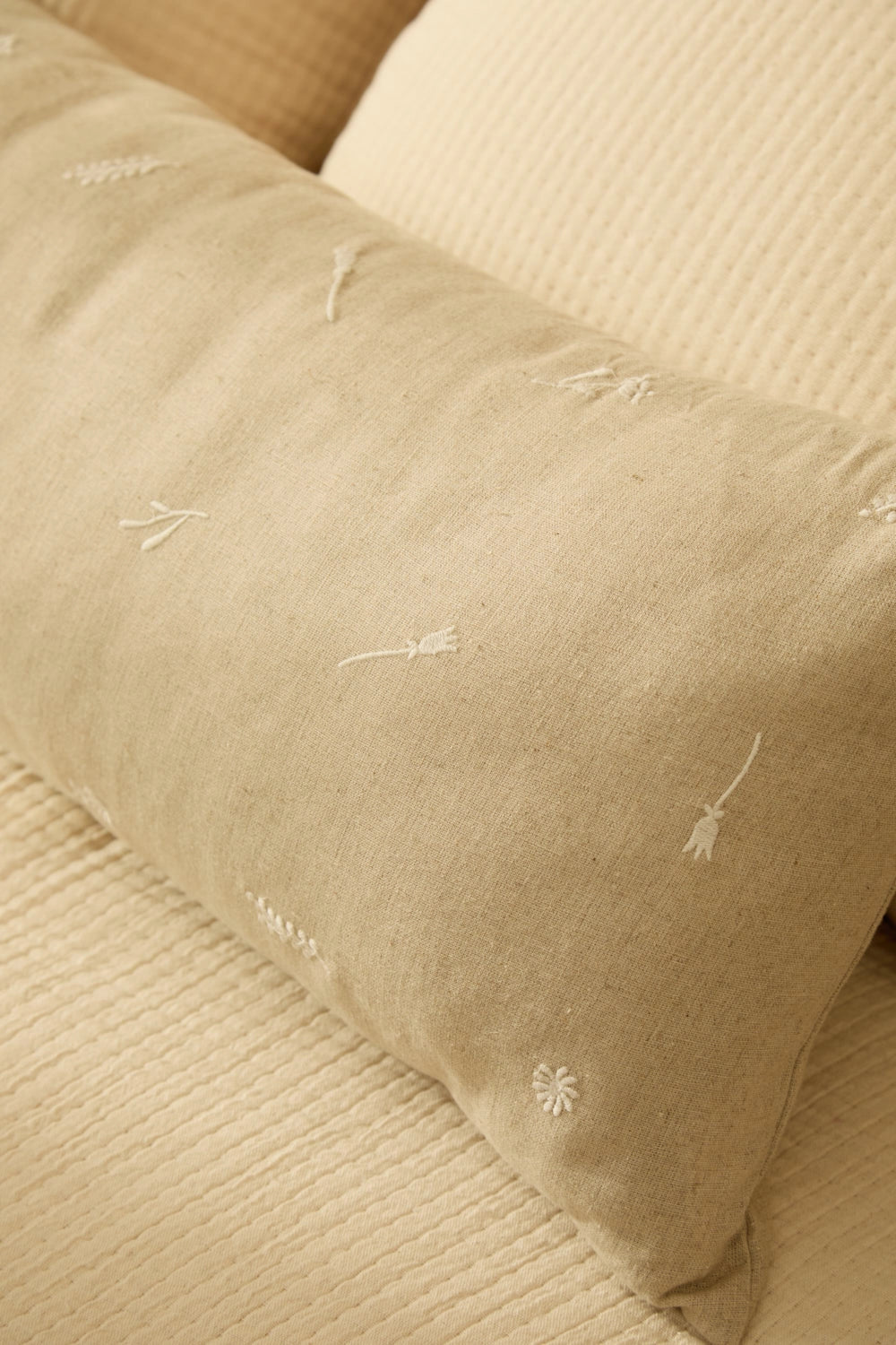 Funda cojín alargada de lino, lyocell y algodón piedra con bordados crudo y textura natural detalle tela