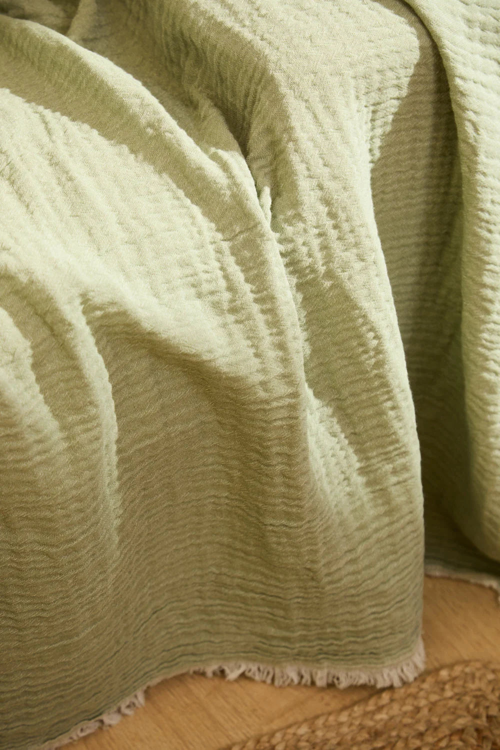 Funda de sofá de muselina de algodón en color verde, con una textura ligera y natural y acabado en flecos tela bajos